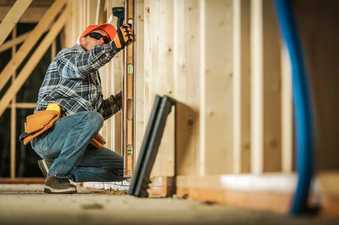 A construction worker checking a wooden frame with a spirit level in NY