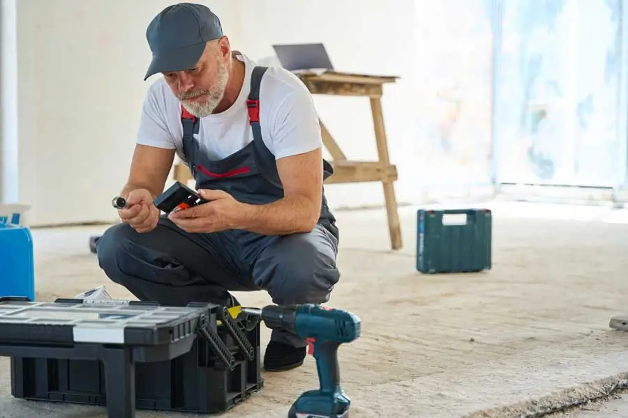 A focused builder sitting near a toolbox looking at layouts